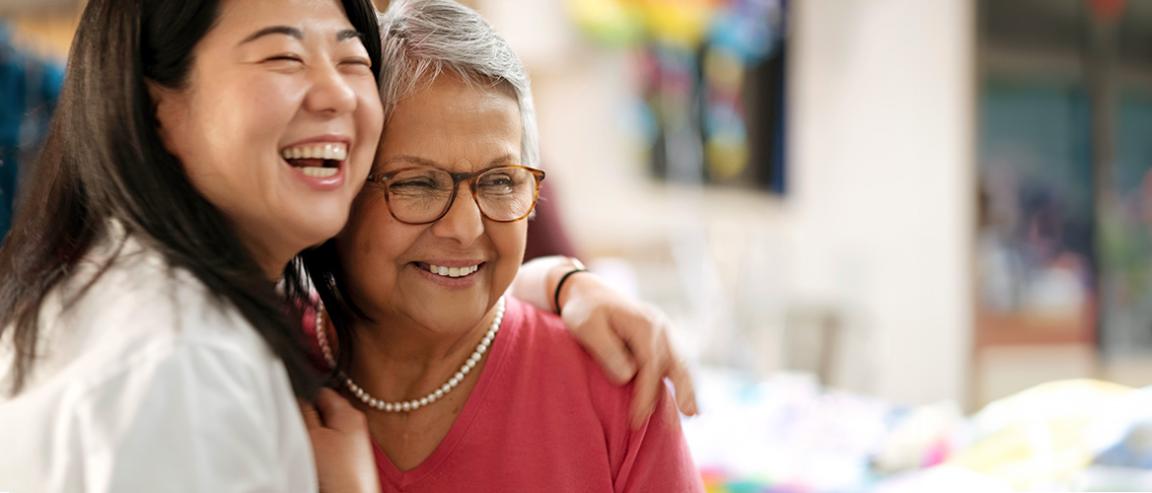 Smiling doctor putting her arm around the shoulder of another smiling person wearing a pink shirt
