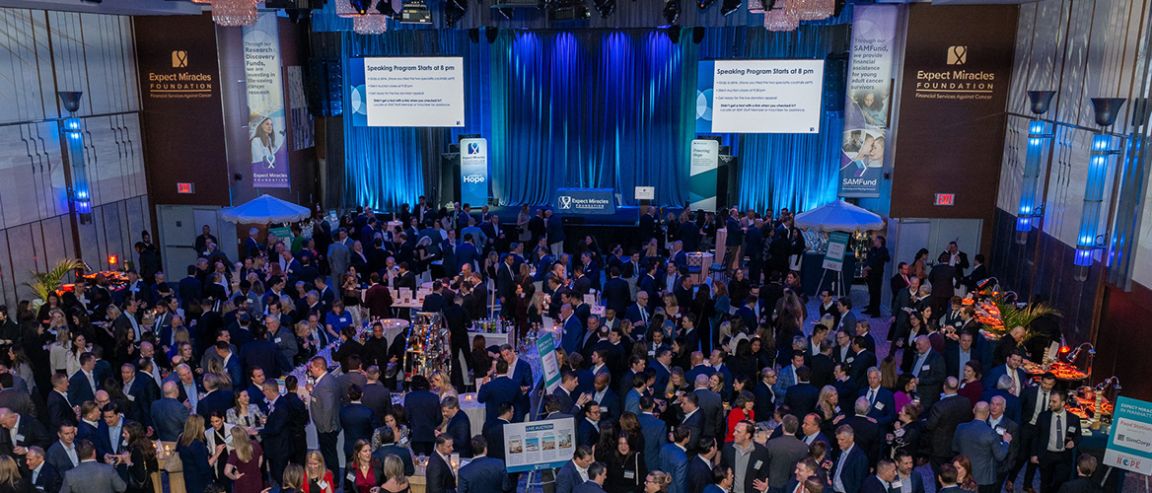 A large crowd gathers at a cancer fundraising event in a ballroom.